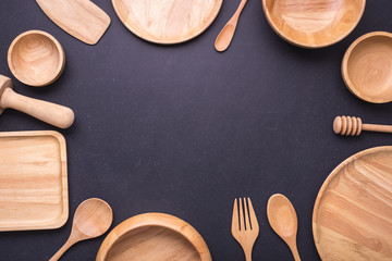 Collection of new wooden kitchen utensil, bowl, plate, spoon, dish. Studio shot on black table....