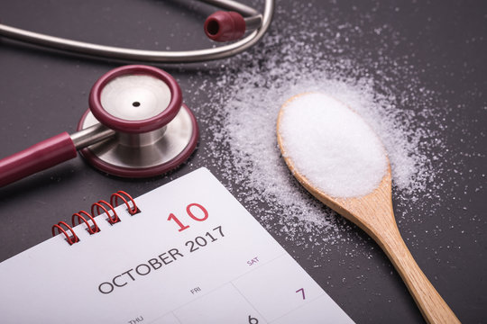 White Salt In Wooden Spoon, Calendar And Doctor Stethoscope On Black Stone Table Background. Healthy And Kidney Concept