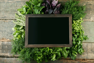 Different fresh herbs with wooden frame on wooden table