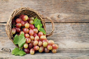 Red grape in basket on grey wooden table