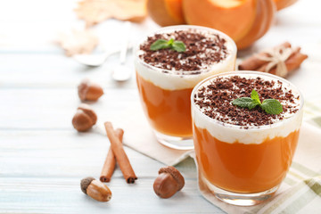 Pumpkin smoothie in glasses with cinnamon and acorns on wooden table