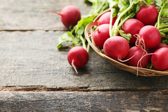 Red radishes in basket on grey wooden table