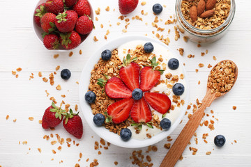 Tasty granola with berries in plate on wooden table