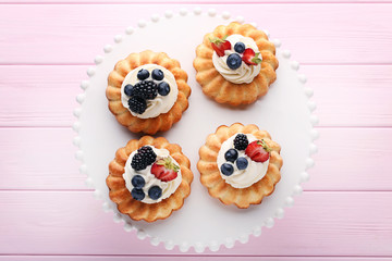 Delicious bundt cakes with berries on pink wooden table