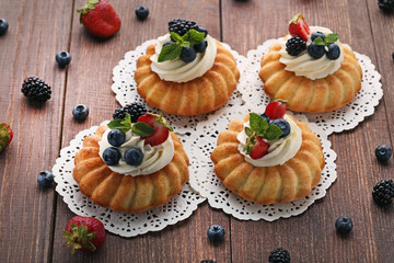 Delicious bundt cakes with berries on brown wooden table