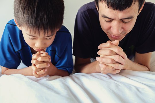 Parent And Child Praying On The Bed