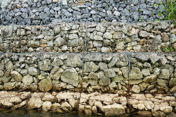 Stones wall in steel mesh cage for block Ground breaking on riverside