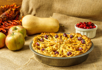 Fall traditional apple pie still life with pumpkin, cranberry and apples.