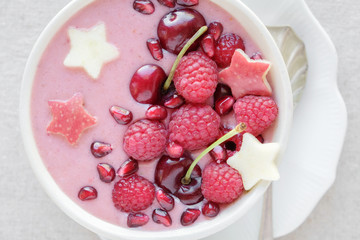 red pink smoothie bowl with cherry, strawberry, raspberries and pomegranate