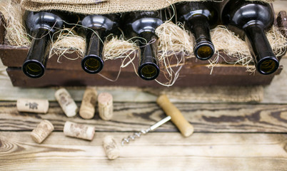 Empty wine bottles in a wooden box on a rustic table. Background