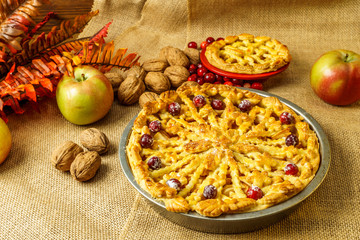 Fall traditional apple pie still life with pumpkin, cranberry and apples.
