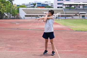 Obraz premium Healthy young Asian runner man warming up before run on track in the stadium