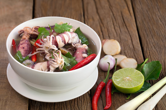 Squid spicy soup (Tom yum) seafood Thailand food in white bowl on brown table