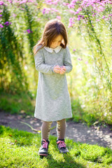 happy little girl is walking in a beautiful park holding a butterfly and playing.