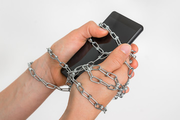 Chain ties together hands and smartphone - addiction concept