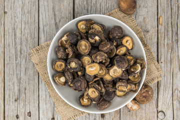 Portion of Shiitake mushrooms (dried) on wooden background, selective focus