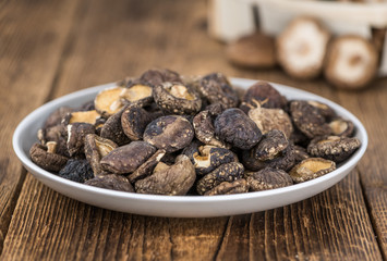 Portion of Shiitake mushrooms (dried) on wooden background, selective focus