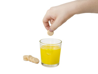 Effervescent medicinal tablet in hand over a glass of solution