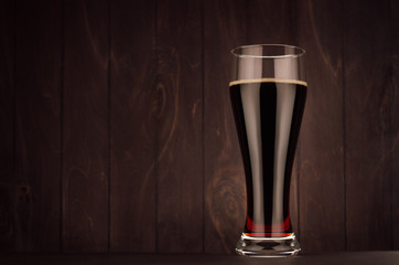 Weizen beer glass porter or red ale on dark wood board, copy space. Template for advertising, design, branding identity, restaurant menu, cover.