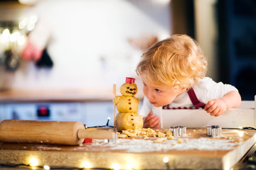 Toddler boy making gingerbread cookies at home.