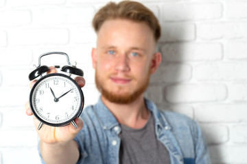 Young handsome man and clock on brick wall