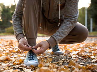 Man lacing his sportive shoes getting ready for jogging in atumn park. Running man outdoors.
