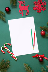 Fototapeta na wymiar Christmas white blank for letter to Santa or your wish list or advent activities on green background. Top view.