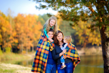 happy family walks in a beautiful autumn park, having fun and hiding behind a rug.