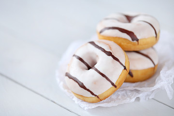 Donut. white striped donuts on white  paper on a light wooden plank background