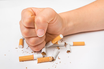Human fist and pile of broken cigarettes - stop smoking concept
