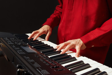 Pianist playing the electronic synth on a black background