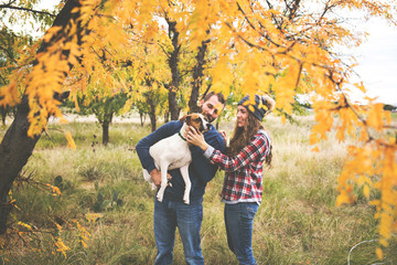 Cute couple playing with their dog in the fall leaves