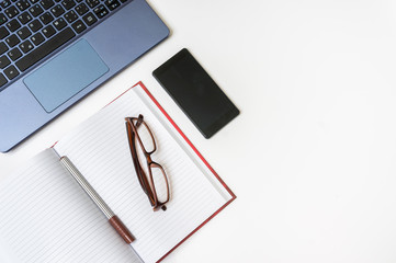Workplace with laptop and smartphone on white wooden table