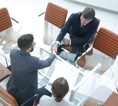 Handshake across the table of financial partners