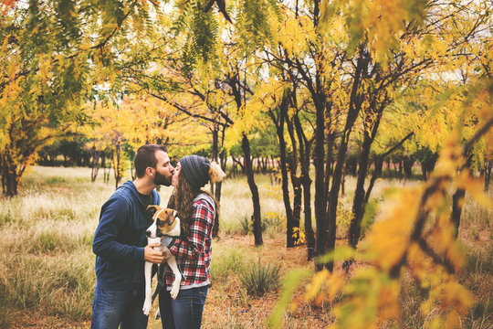 Cute Couple Playing With Their Dog In The Fall Leaves