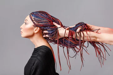 Foto op Plexiglas Kapsalon Kleurrijke haarvlechten met kanekalon Zizi in de handen van een kapper, creativiteit en modieus kapselconcept