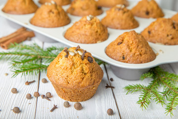 Christmas cupcakes with spices cloves, seeds and nuts in a baking dish on white wooden table