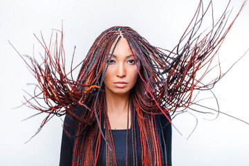 Conceptual studio shot of a modern creative woman with colorful flying braided dreads © EdNurg
