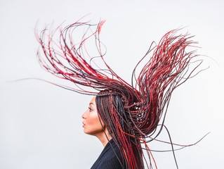Conceptual studio shot of a modern creative woman with colorful flying braided dreads © EdNurg