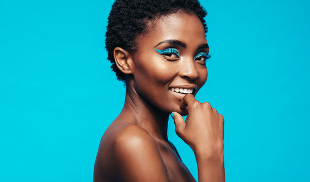Woman with makeup smiling against blue background