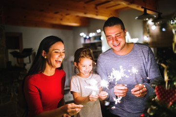 Young family with sparklers at Christmas time at home.