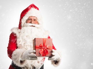 Santa Claus holding a bag with presents over a white/gray background  © Tijana