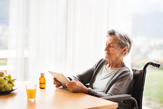 Senior woman in a wheelchair with tablet at home.