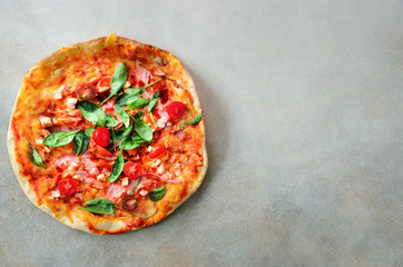 Fresh italian pizza with mushrooms, ham, tomatoes, cheese, olive, pepper on grey concrete background. Copy space. Top view.