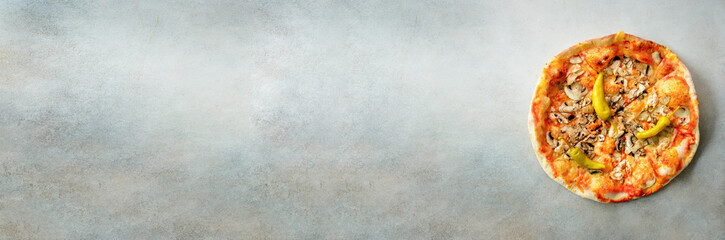 Fresh italian pizza with mushrooms, ham, tomatoes, cheese, olive, pepper on grey concrete background. Copy space. Top view. Banner
