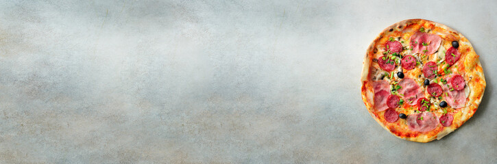 Fresh italian pizza with mushrooms, ham, tomatoes, cheese, olive, pepper on grey concrete background. Copy space. Top view. Banner