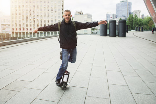 Casual man riding on one wheel electronic monocycle in the city.