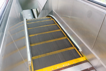 Obraz premium Escalator in metro. Moving up staircase. escalator. electric escalator.Close up to escalators. electric escalator.Close up floor platform. yellow bands. metal line steel. yellow gray steel line.Moving