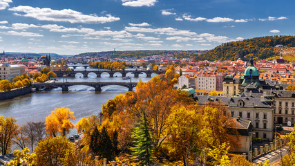 View to the historical bridges, Prague old town and Vltava river from popular view point in the Letna park (Letenske sady), beautiful autumn landscape in soft yellow light, Czech Republic