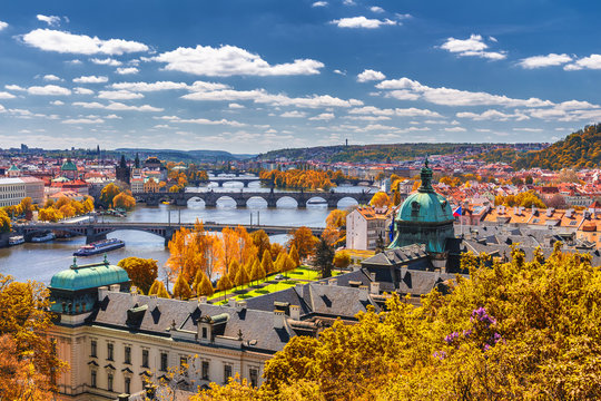View to the historical bridges, Prague old town and Vltava river from popular view point in the Letna park (Letenske sady), beautiful autumn landscape in soft yellow light, Czech Republic